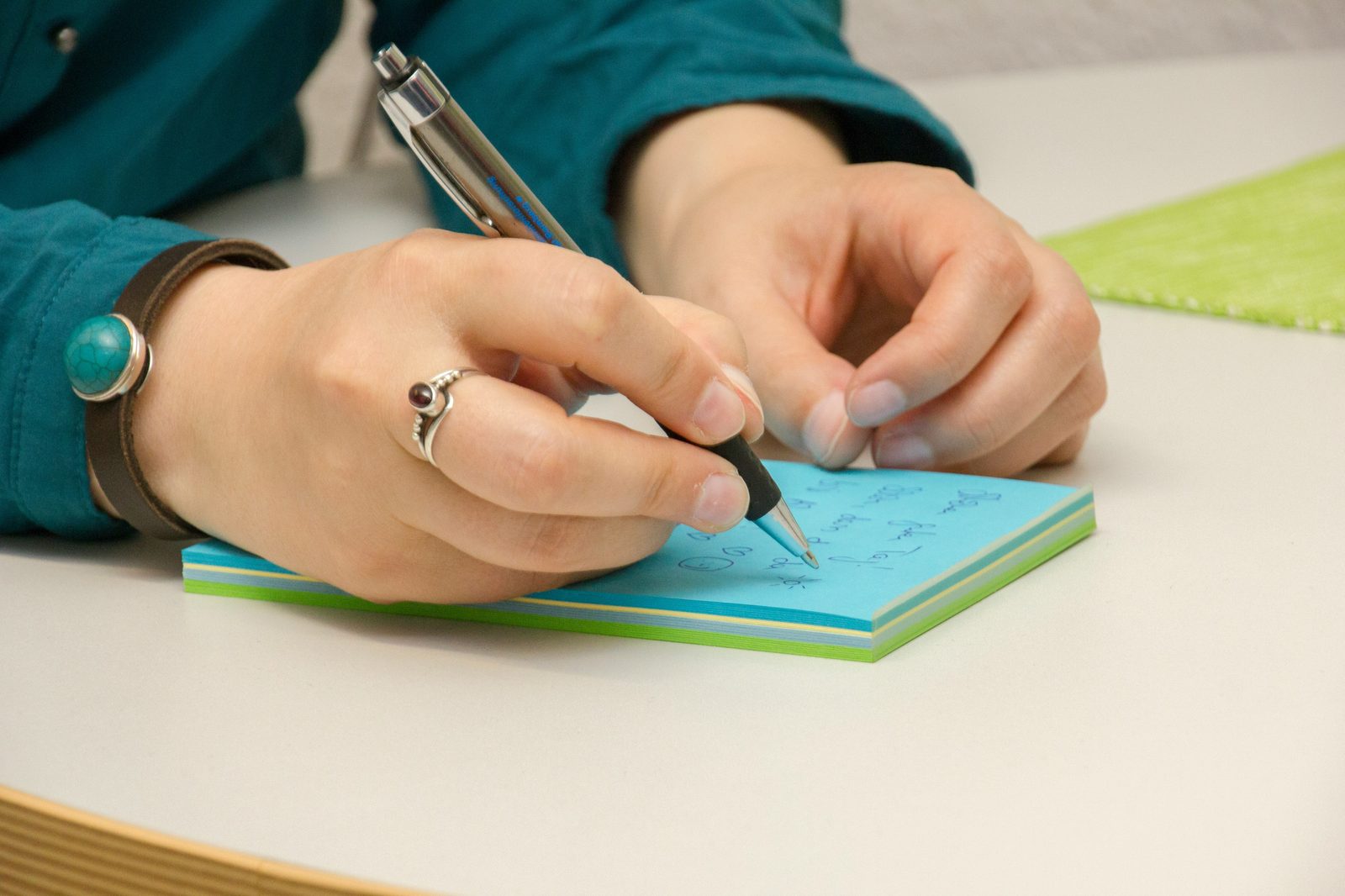 A hand jotting a note on colored paper